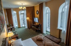 ein Hotelzimmer mit Bett, Schreibtisch und Fenstern in der Unterkunft Premier Hotel Palazzo in Poltawa + 50 Fotos