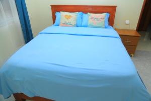 a large bed with blue sheets and pillows at Celesta House in Mbarara