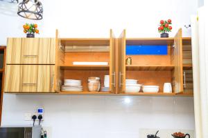 a kitchen with wooden cabinets with plates and bowls at Celesta House in Mbarara +5 photos