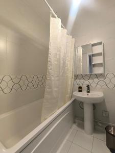 a white bathroom with a sink and a shower curtain at Zolu apartment in Ulaanbaatar