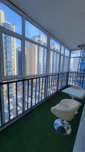 a room with a white chair on a balcony with windows at Zolu apartment in Ulaanbaatar