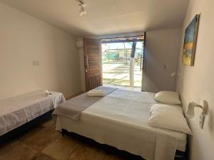a bedroom with two beds and a door to a yard at BRKITE Pousada in Cumbuco