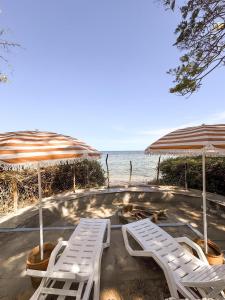 two white lounge chairs and umbrellas on the beach at Attalah Beach Cottage in Mombasa