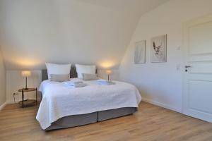 a bedroom with a large white bed with two lamps at Das Reethaus in Groß Schwansee +24 photos