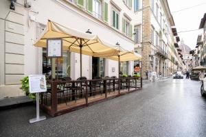 a restaurant with tables and umbrellas on a street at Glimpse Hotel in Florence
