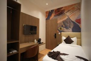 a hotel room with a bed and a desk and a tv at NE Heritage Residency in Guwahati