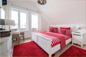 a white bedroom with a red and white bed with a red rug at Kapitänsweg 12 in Karlshagen