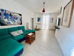 a living room with a green couch and a tv at Al Castello - UN LETTO IDEALE in Gaeta