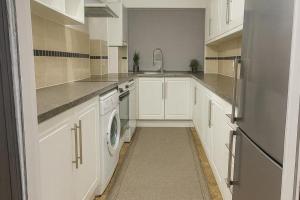 a kitchen with white cabinets and a washer and dryer at House-Sleeps 5 person -Etihad Stadium 15 min drive in Ashton under Lyne