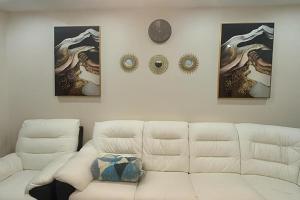 a living room with a white couch and a clock at House-Sleeps 5 person -Etihad Stadium 15 min drive in Ashton under Lyne