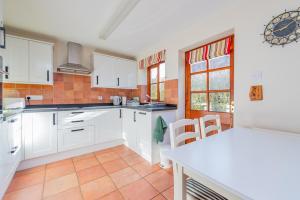 a kitchen with white cabinets and a table and chairs at Willow Cottage in North Lydbury