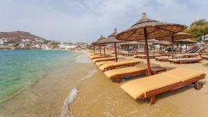 a row of beach chairs and umbrellas on a beach at Asteri Hotel in Ornos