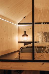 a bed in a wooden room with a hanging light at Rusty Cabin -Tiny House in Neustift an der Lafnitz