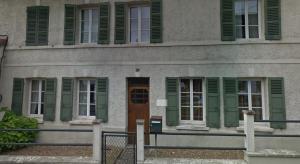 a building with green shutters and a wooden door at Chez AB studio cosy in Beauvais