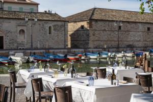a group of tables and chairs with boats in the water at Hotel alla Grotta in Lazise