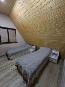 two beds in a room with a wooden ceiling at A-frame , Quba Qecres in Qǝçrǝş