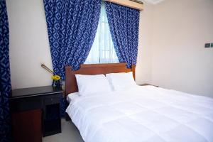 a bedroom with a white bed and a window at Aduk Guest House Airport City Accra in Otele