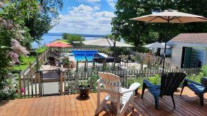 a deck with chairs and tables and an umbrella at La maison de l'île d'Orléans - B&B - déjeuner gastronomique in Saint-Jean