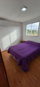 a purple bed in a room with a window at Solar de la Viuda in Punta Del Diablo +40 photos