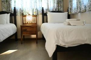 a bedroom with two beds and a table with a lamp at Ongersfontein gasteplaas in Richmond
