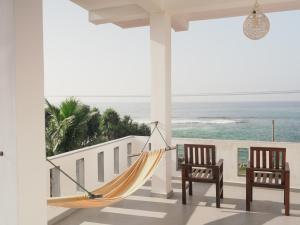 a hammock on the porch of a house overlooking the ocean at Shehara Sun Surf Lodge in Midigama East