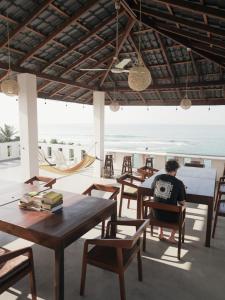 a man sitting at a table looking out at the ocean at Shehara Sun Surf Lodge in Midigama East