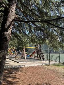 a park with a playground with a tree at mtatsminda residence in Itʼkhvisi