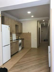 a kitchen with a white refrigerator and wooden cabinets at mtatsminda residence in Itʼkhvisi