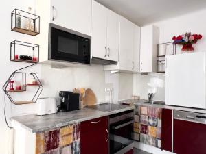 a kitchen with white cabinets and a tv on the wall at Alpenresidenz Viktoria in Türnitz