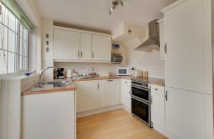a kitchen with white cabinets and a sink at 2 Bed in Instow oc-stones in Instow +15 photos