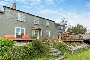a green house with a wooden deck in front of it at 4 Bed in Goodleigh oc-e29107 in Goodleigh