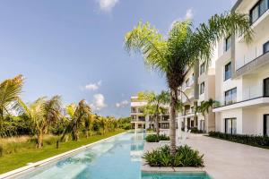 a swimming pool with a palm tree in front of a building at Cana Cove in Punta Cana