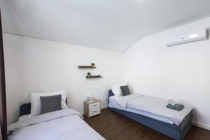 two beds in a room with white walls and wooden floors at Aeris Residence Panoramic View in Sarajevo
