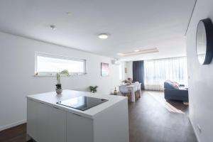a white kitchen with a sink and a living room at Aeris Residence Panoramic View in Sarajevo