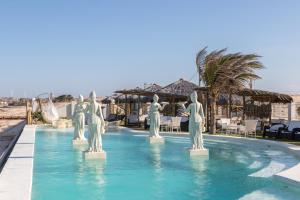 a swimming pool with statues in the water at Positano Village in Canoa Quebrada