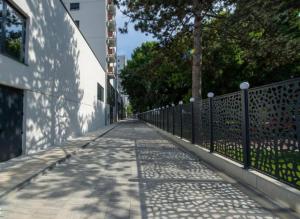 an empty sidewalk with a fence and trees on the side of a building at Apartmani Katnic in Jagodina