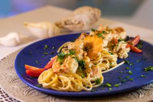 a blue plate of shrimp pasta on a table at Positano Village in Canoa Quebrada