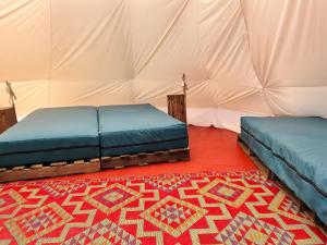 a room with two beds and a rug in a tent at Arkeo - Luxury tents and cabins at the river in Nonceveux +22 photos