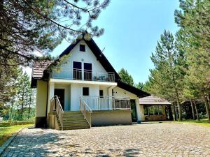 a white house with a balcony and a driveway at Calm Stay Blidinje in Blidinje