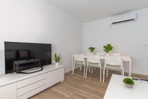 a white living room with a dining table and a television at Hauzify I Apartament Pedrera in Tarragona