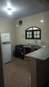 a kitchen with a white refrigerator and a sink at casa de praia grande e espaçosa in Bertioga