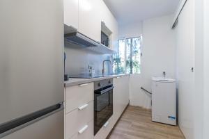 a kitchen with white cabinets and a sink at Hauzify I Apartament Pedrera in Tarragona