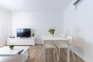 a white dining room with a white table and chairs at Hauzify I Apartament Pedrera in Tarragona