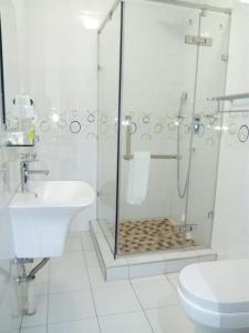 a white bathroom with a shower and a sink at Voyager Inn-Hotel in Palatswe +20 photos