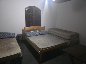 a small room with a bed and a couch at casa de praia grande e espaçosa in Bertioga