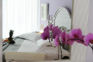 a bedroom with a bed with a mirror and purple flowers at San Nicolas Resort Hotel in Mikros Gialos