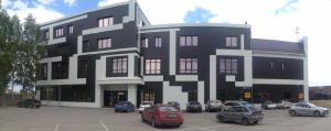 a black and white building with cars parked in a parking lot at Sport Hotel Maximum in Kemerovo