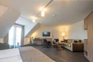 a living room with a couch and a desk at Flair Park Hotel Ilshofen in Ilshofen