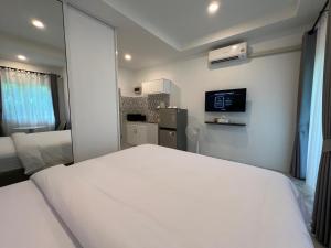 a bedroom with a white bed and a television at Sarona House 3 in Ban Thalat Choeng Thale