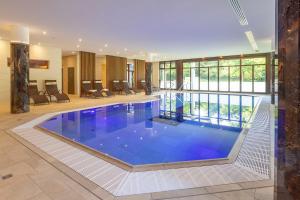 a large swimming pool in a house with a lobby at Flair Park Hotel Ilshofen in Ilshofen